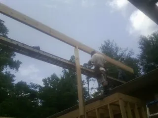 Carpenter setting a ridge beam over a new addition frame — Ice Dam Removal by Roofing Brothers in Campaign