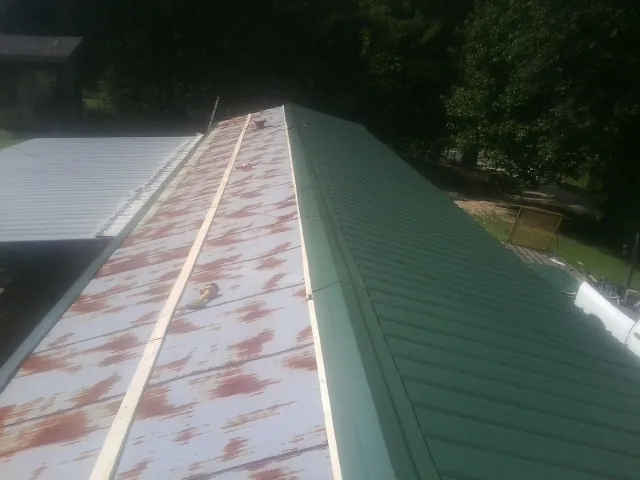 Old rusted panels beside newly installed green metal roofing — Wind Damage Roof Repair by Roofing Brothers in Campaign