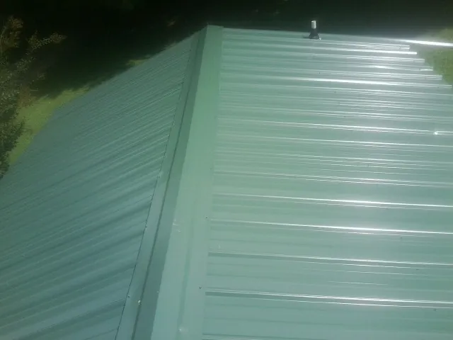 New green metal panels meeting at the ridge of a roof — Flat Roof Repair work by our crew in Campaign