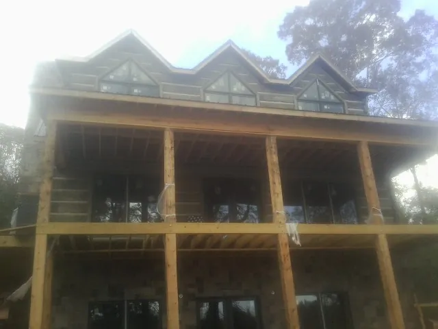 Dormers and porch framing on a large log home under construction — Roof Coating work by our crew in Campaign