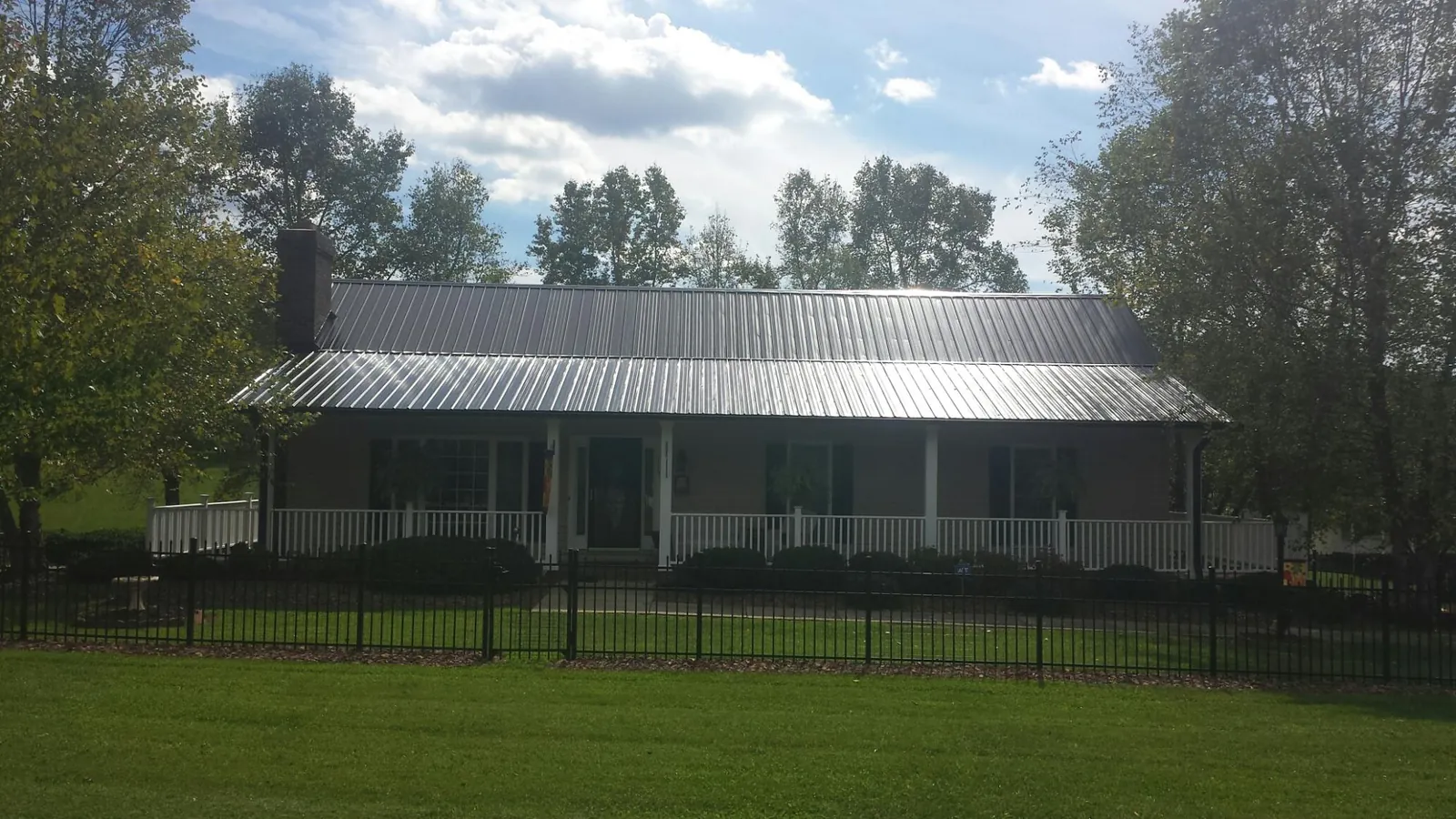 Gray metal roof on a brick ranch with a full width front porch — Gutter Guard Installation work by our crew in Campaign