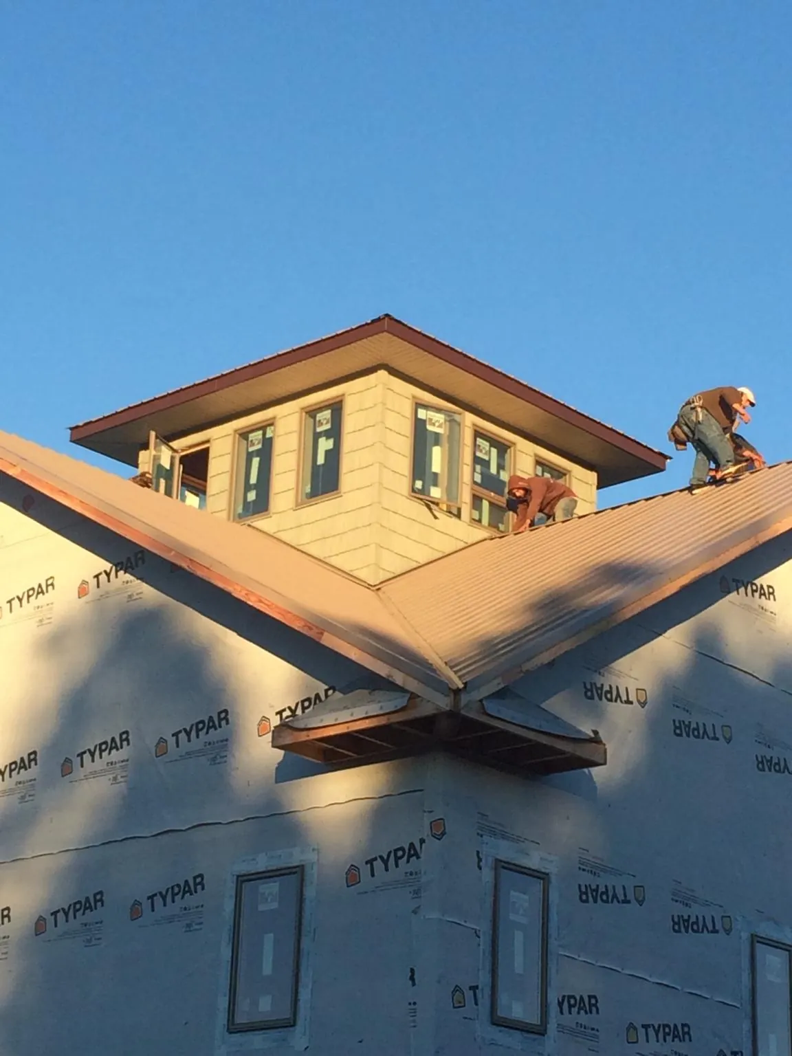 Roofers working around a rooftop cupola on a new metal roof at sunset — Roof Waterproofing in Campaign by Roofing Brothers